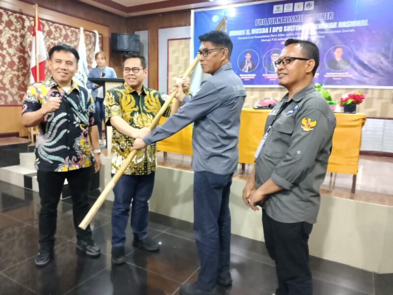 Caption: Ketua Dewan Pakar DPP PJS, Rizaludin Kurniawan saat menyerahkan Pataka PJS kepada Ketua DPP PJS Terpilih Mahmud Marhaba usai Munas II, Palu (13/07/2025).