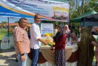 Caption : SEVP Business Support PTPN IV regional 6 Ifri Handi Lubis menyerahkan beras SPHP langsung ke pembelinya